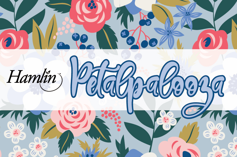 A promotional banner for "Hamlin Petalpalooza" featuring a floral pattern. The top and bottom borders display a colorful array of stylized flowers and leaves in shades of pink, blue, white, and green. The center has a white background with the words "Hamlin Petalpalooza" written in elegant, cursive fonts. The word "Hamlin" is in black, while "Petalpalooza" is in a light blue script with a darker blue outline. The floral designs add a vibrant and festive feel to the banner.