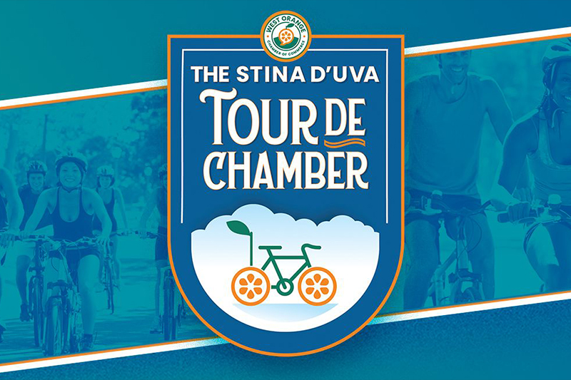 Promotional image for "The Stina D'Uva Tour de Chamber," organized by the West Orange Chamber of Commerce. The design features a central shield-shaped logo with the event name in bold, stylized lettering. Below the text, there is an illustration of a bicycle with wheels resembling orange slices, set against a backdrop of clouds. The background includes images of cyclists in motion, overlaid with a blue-green color tone. The West Orange Chamber of Commerce logo is displayed at the top of the shield.